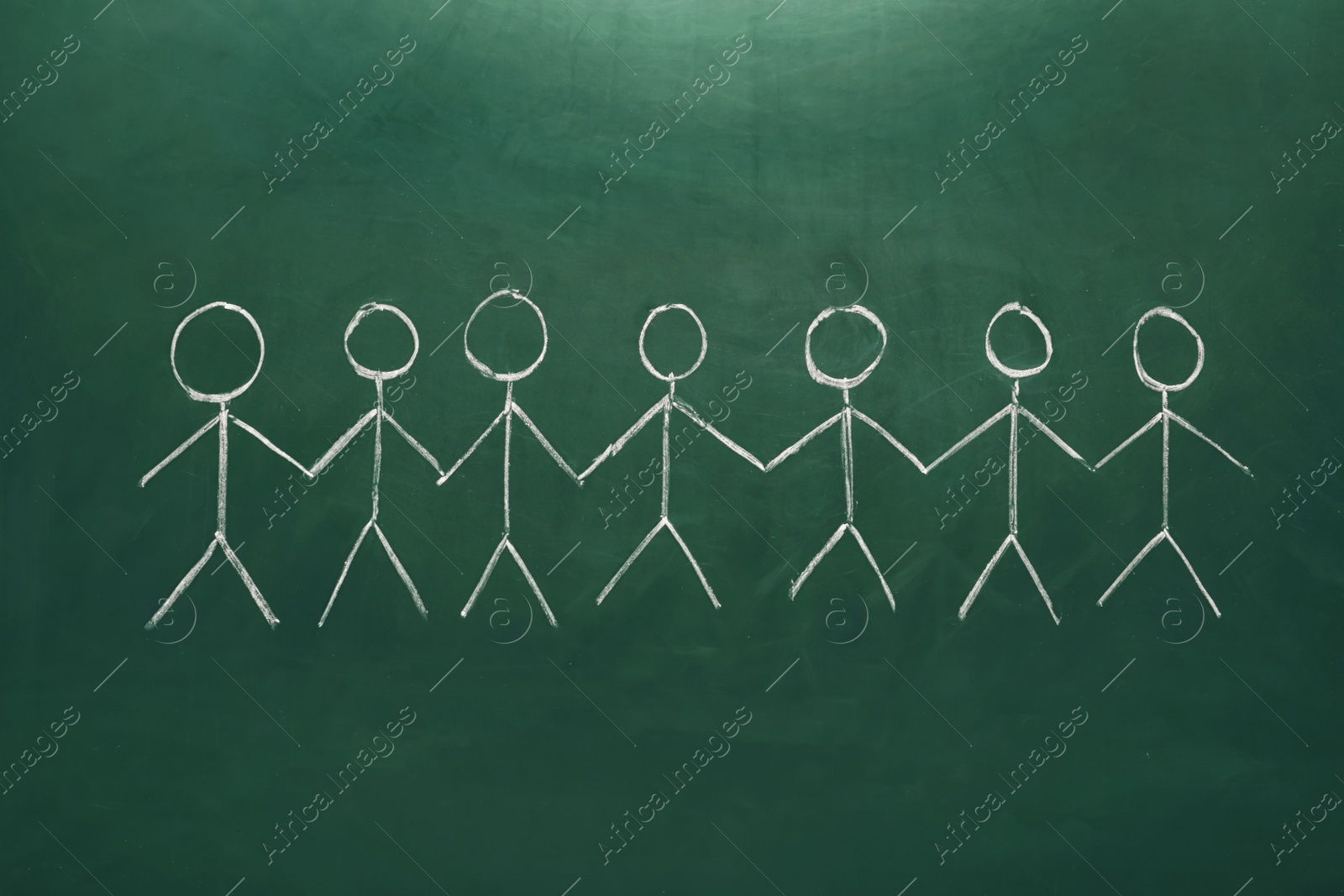 Photo of Drawing of people holding hands together on chalkboard. Unity concept