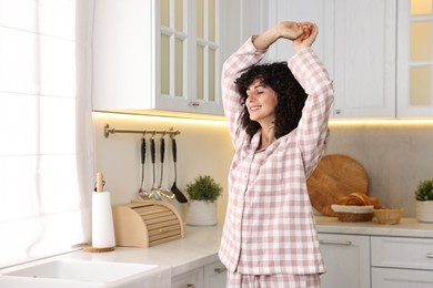 Photo of Beautiful young woman in stylish pyjama in kitchen