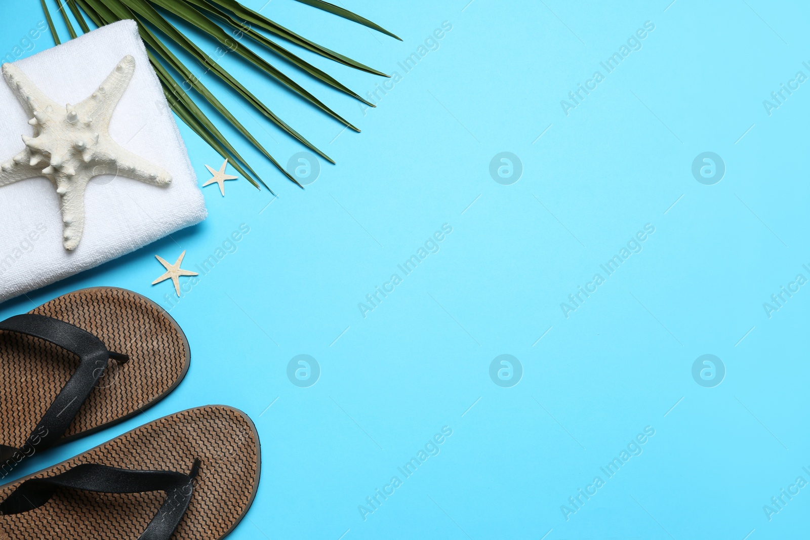 Photo of Flat lay composition with beach flip flops on light blue background. Space for text