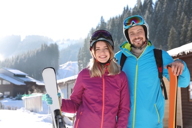 Photo of Happy couple with ski equipment spending winter vacation at mountain resort