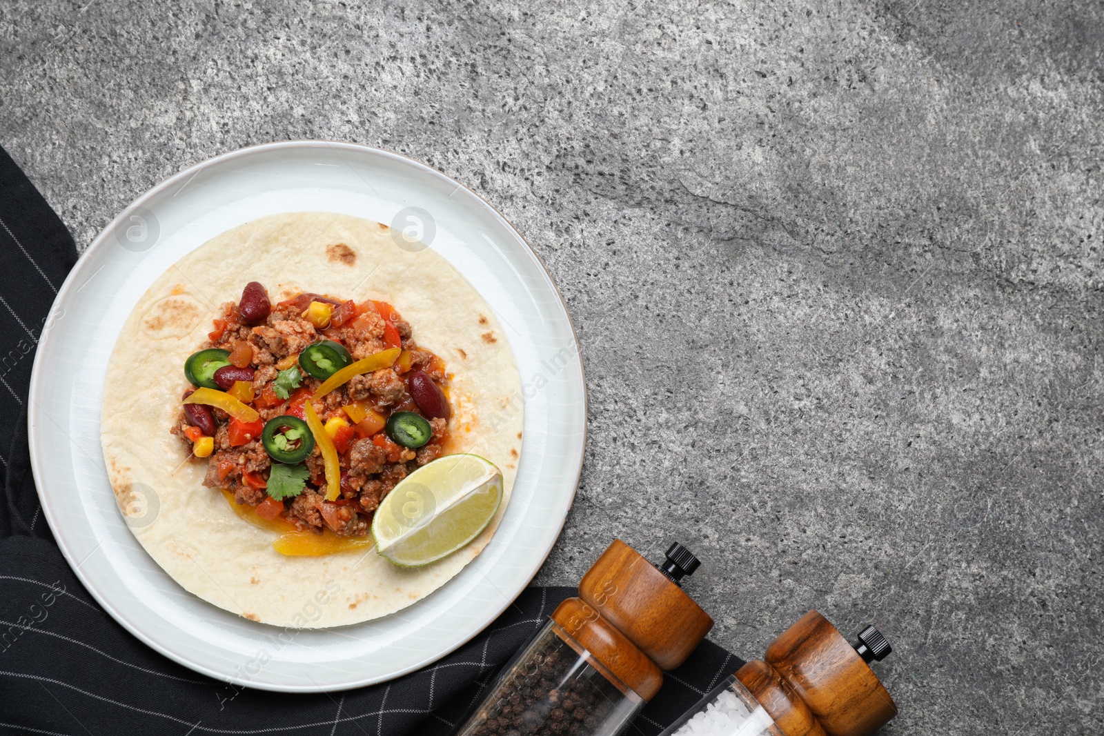 Photo of Tasty chili con carne with tortilla on grey table, flat lay. Space for text