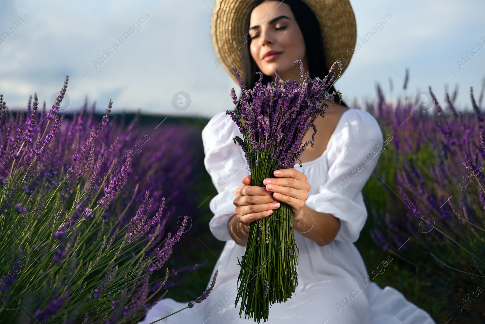 Photo of Beautiful young woman with bouquet in lavender field