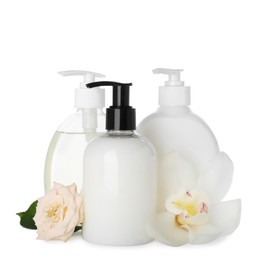 Photo of Dispensers of liquid soap and beautiful flowers on white background