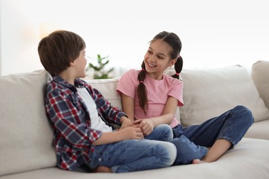 Photo of Happy brother and sister spending time together on sofa at home