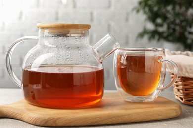 Photo of Aromatic tea in glass cup and teapot on table