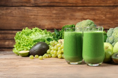 Photo of Glasses of fresh green smoothie and ingredients on wooden table, space for text