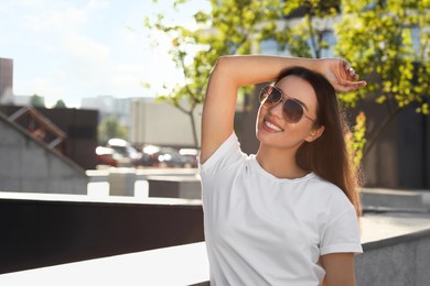 Photo of Beautiful smiling woman in sunglasses on city street, space for text