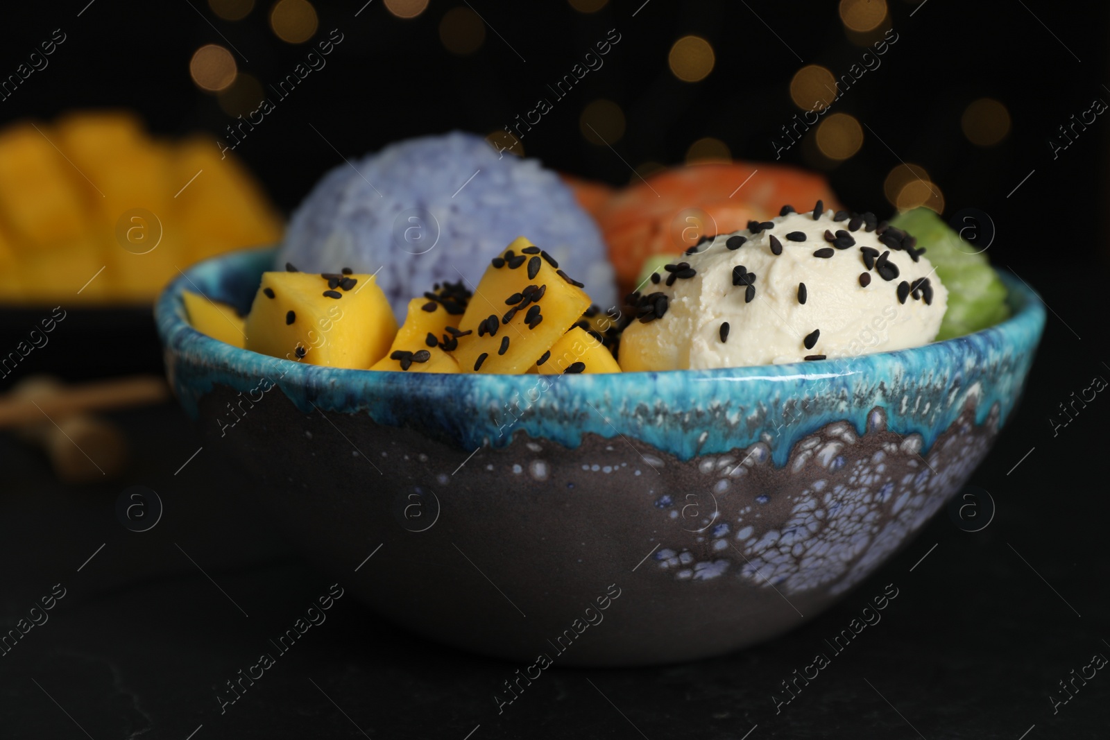 Photo of Delicious poke bowl on table against blurred lights, closeup