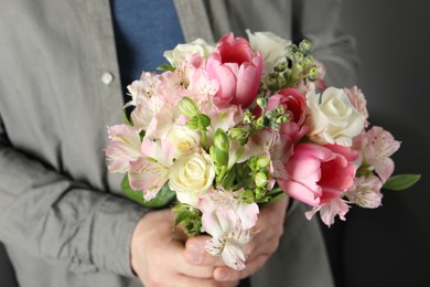 Photo of Man holding bouquet of beautiful flowers indoors, closeup