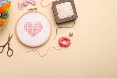 Photo of Flat lay composition with embroidery and different sewing accessories on beige background. Space for text