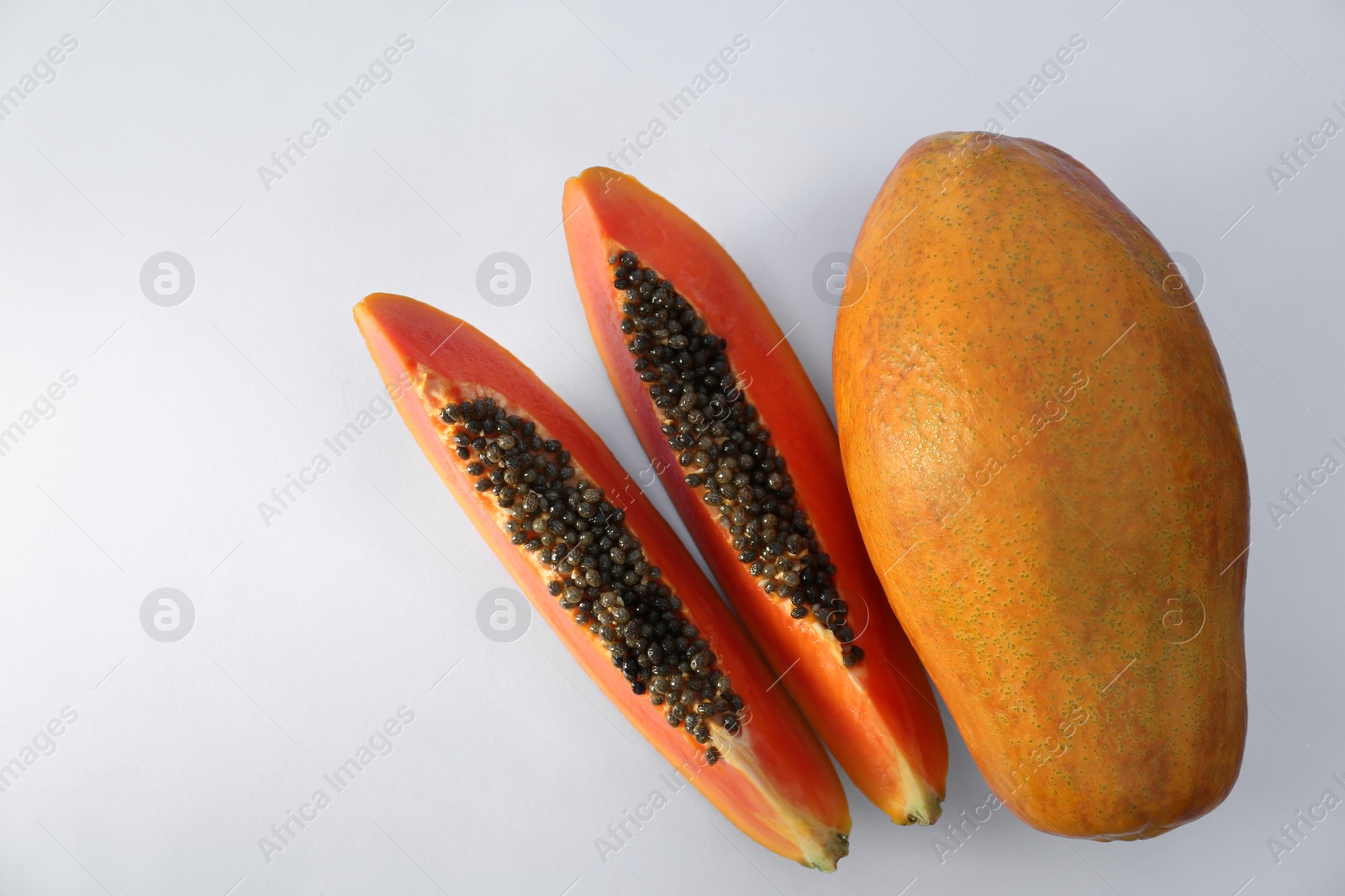 Photo of Fresh ripe cut and whole papaya fruits on white background, flat lay. Space for text