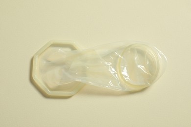 Unrolled female condom on beige background, top view. Safe sex