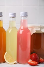 Photo of Delicious kombucha in glass bottles, jar and fresh fruits on white table