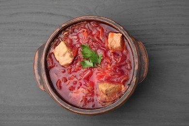 Photo of Tasty borscht in bowl on grey wooden table, top view
