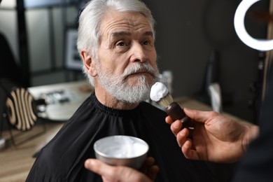 Photo of Professional barber working with client's mustache in barbershop