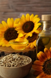 Sunflower, bottle of oil and seeds on table, closeup