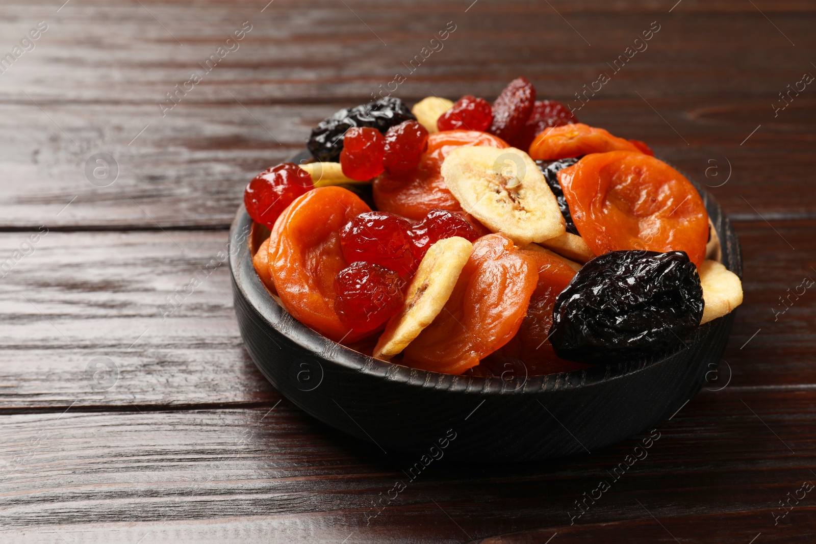 Photo of Mix of delicious dried fruits on wooden table