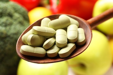 Photo of Dietary supplements. Spoon with pills over food products, closeup