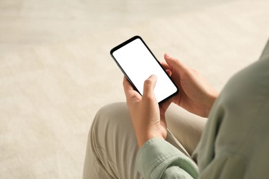 Photo of Young woman using smartphone indoors, closeup view