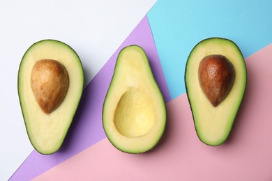 Cut fresh ripe avocados on color background, flat lay