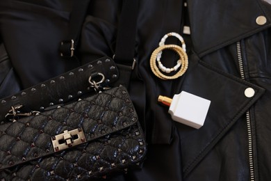 Photo of Bracelets, bottle of perfume, bag and black leather jacket , flat lay