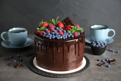 Photo of Freshly made tasty chocolate cake decorated with berries on grey table