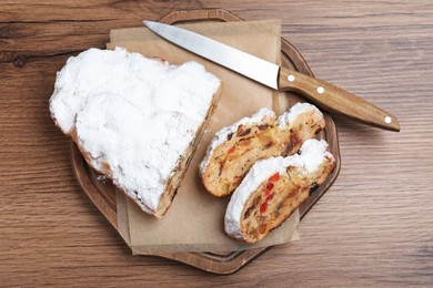 Photo of Traditional Christmas Stollen with icing sugar on wooden table, top view