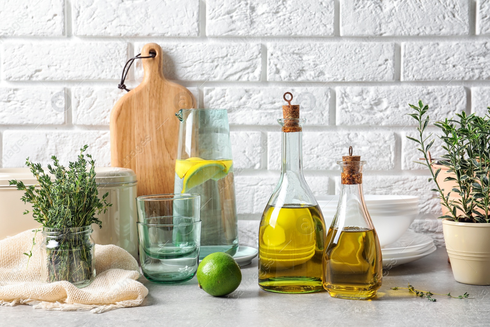 Photo of Fresh olive oil and kitchen utensils on table near brick wall