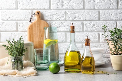 Photo of Fresh olive oil and kitchen utensils on table near brick wall