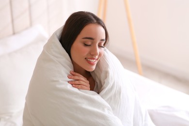 Beautiful young woman wrapped with soft blanket at home