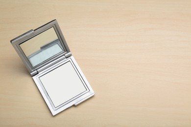 Photo of Stylish cosmetic pocket mirror on wooden table, top view. Space for text