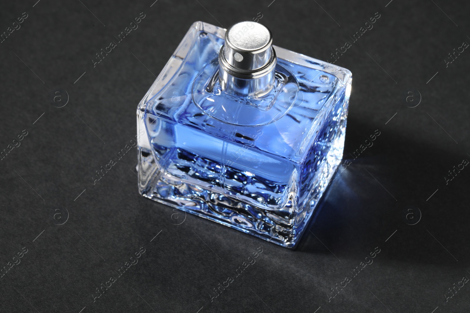 Photo of Blue men's perfume in bottle on black background, closeup