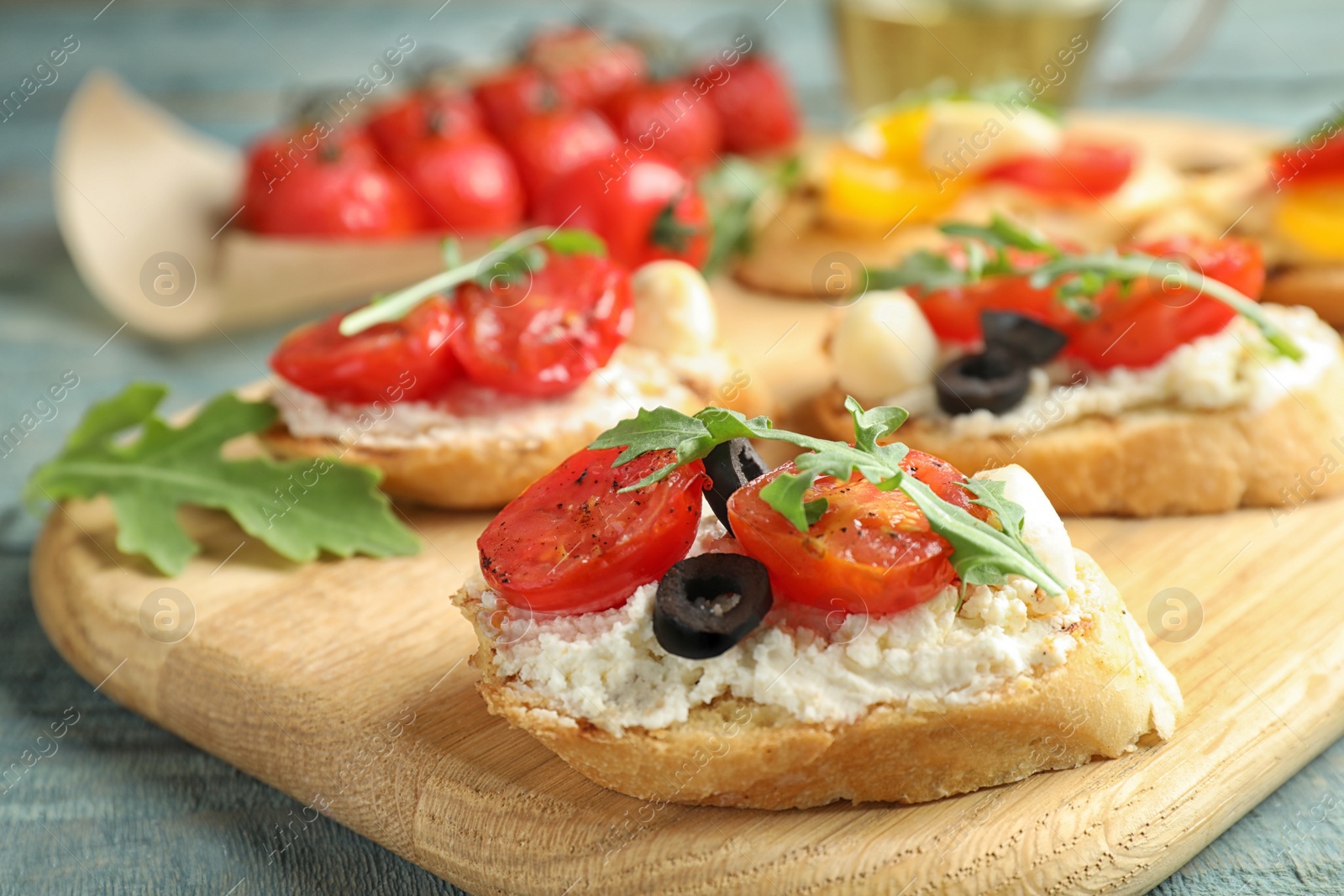 Photo of Wooden board with delicious tomato bruschettas on table, closeup