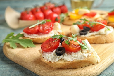 Wooden board with delicious tomato bruschettas on table, closeup