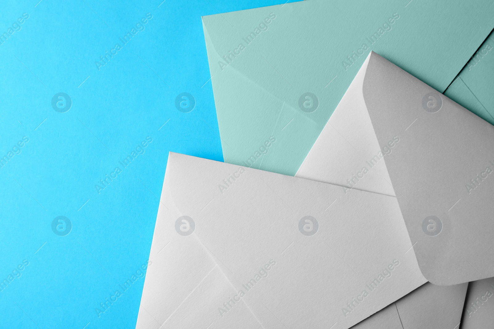 Photo of White paper envelopes on light blue background, flat lay