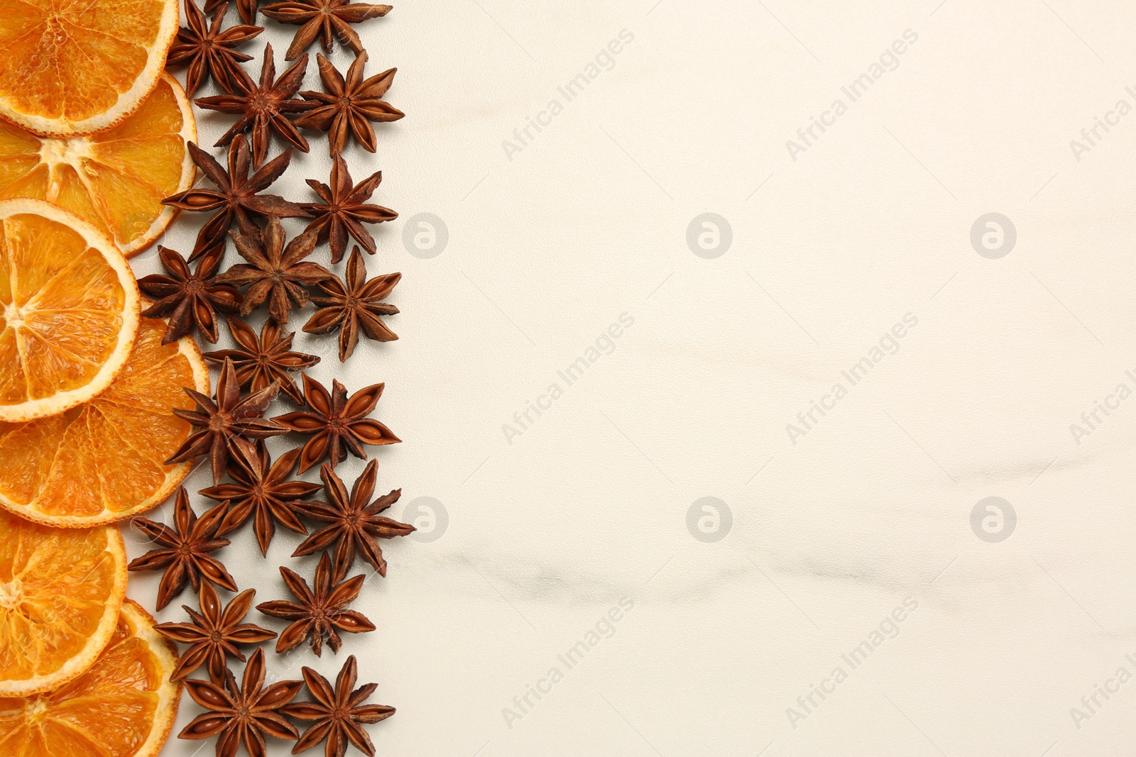 Photo of Dry orange slices and anise stars on white marble table, flat lay with space for text