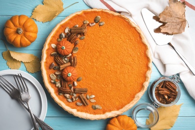 Photo of Delicious homemade pumpkin pie on light blue wooden table, flat lay