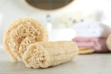Natural loofah sponges on table in bathroom, closeup. Space for text