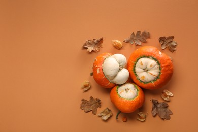 Photo of Fresh ripe pumpkins and dry leaves on orange background, flat lay. Space for text