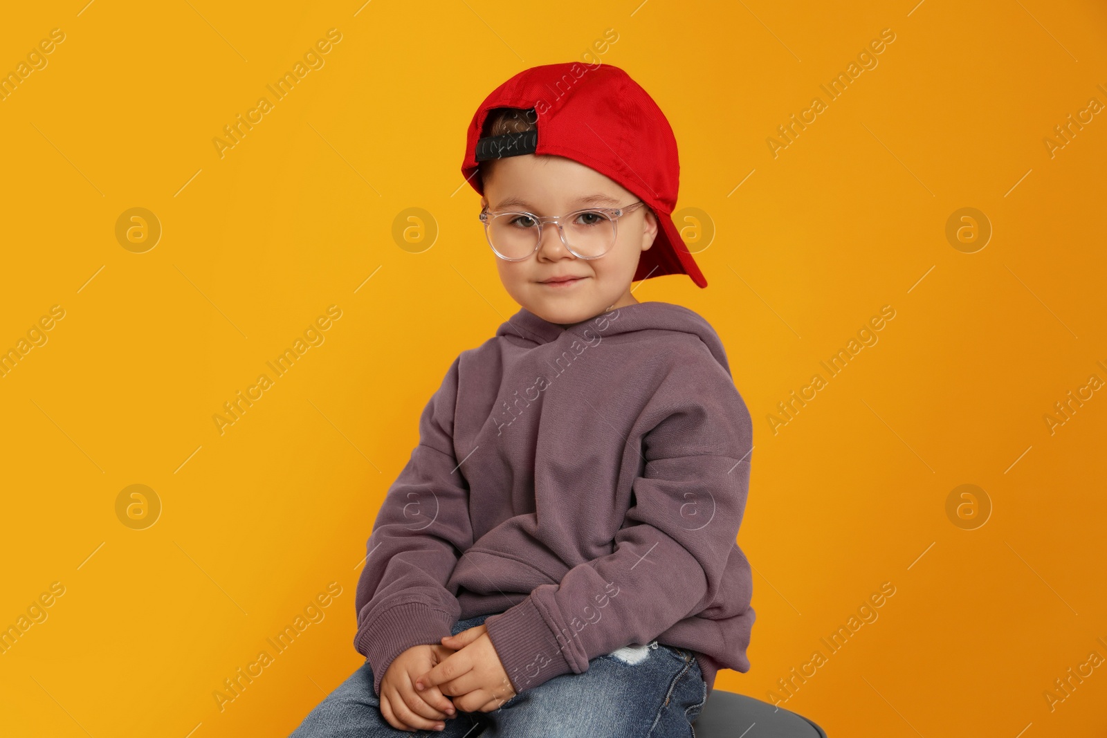 Photo of Cute little boy in glasses on orange background