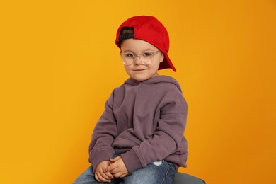 Cute little boy in glasses on orange background