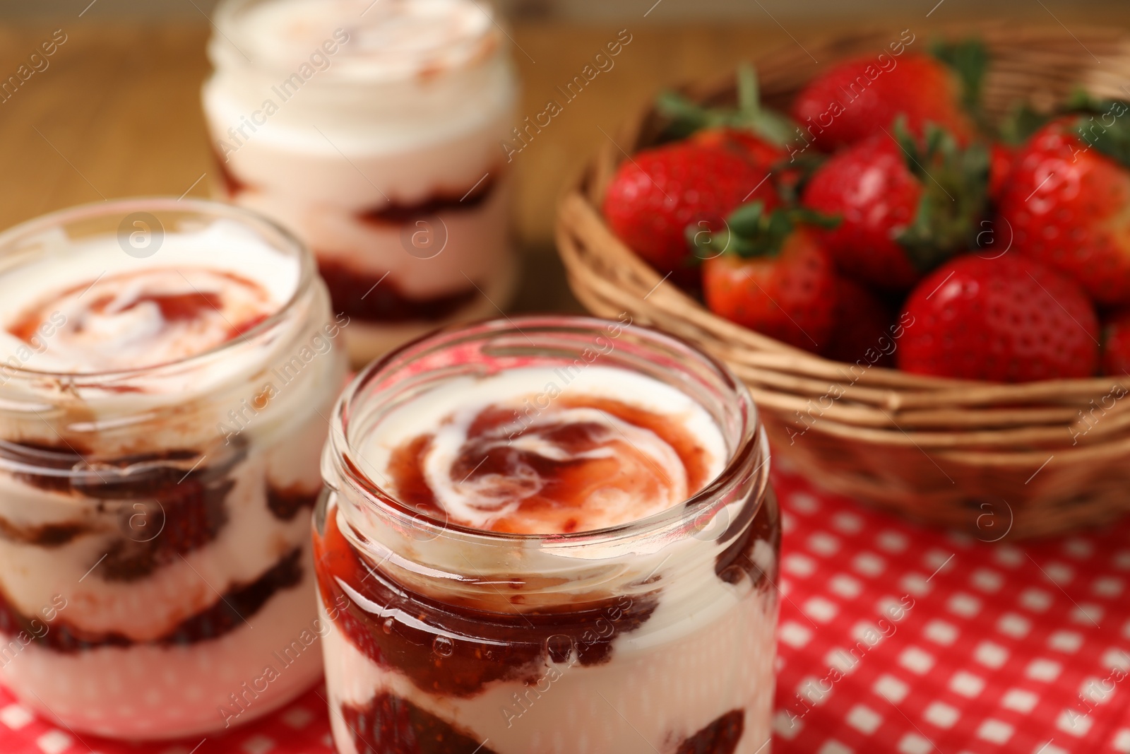 Photo of Tasty yoghurt with jam and strawberries on table, closeup