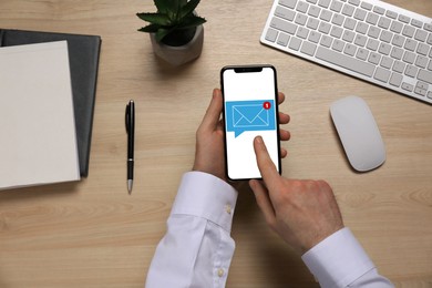 Image of Man checking new message on mobile phone at table, top view