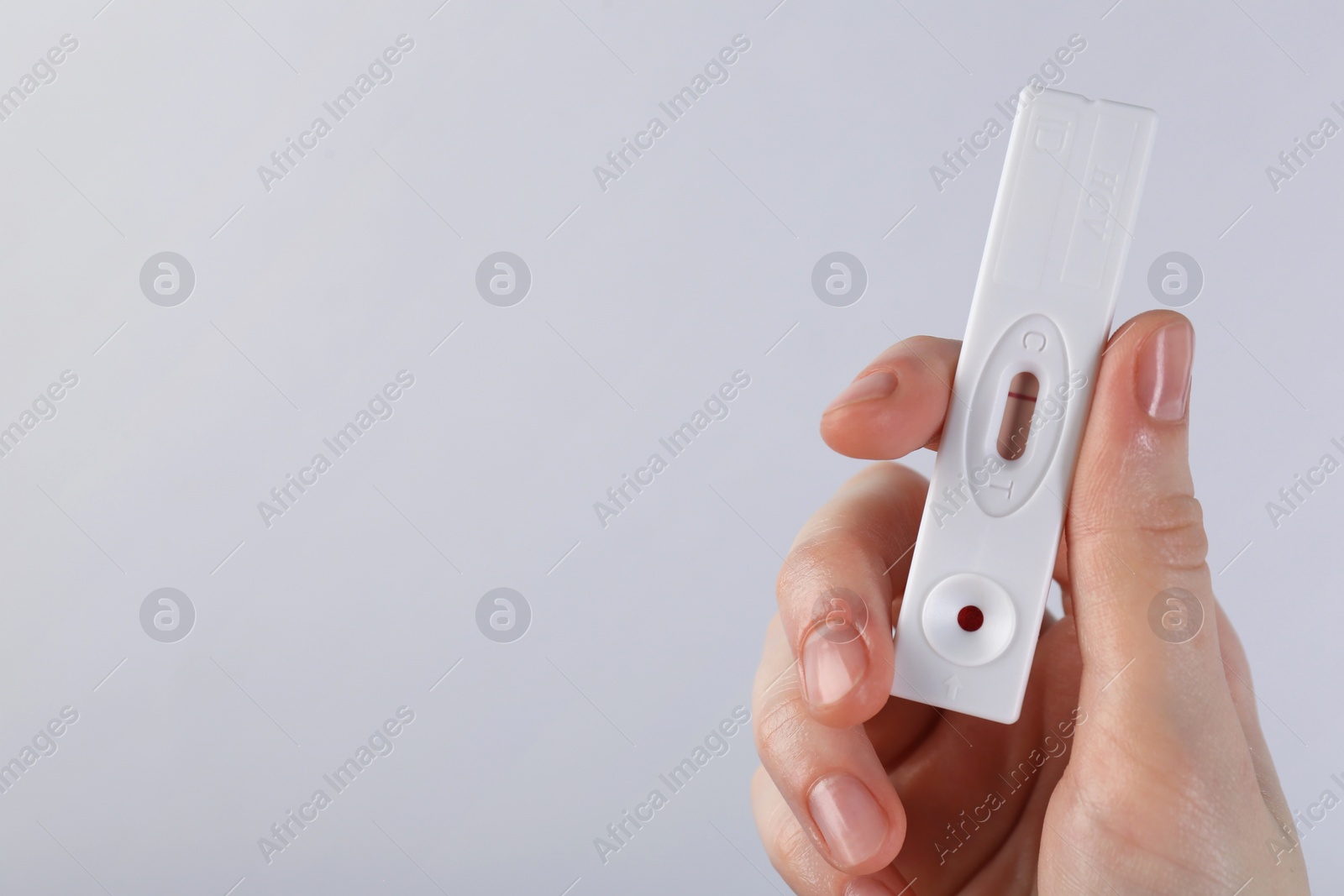 Photo of Woman holding disposable express test on light background, closeup. Space for text