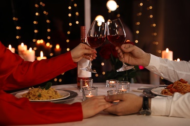 Photo of Couple clinking glasses of wine in restaurant, closeup. Romantic dinner