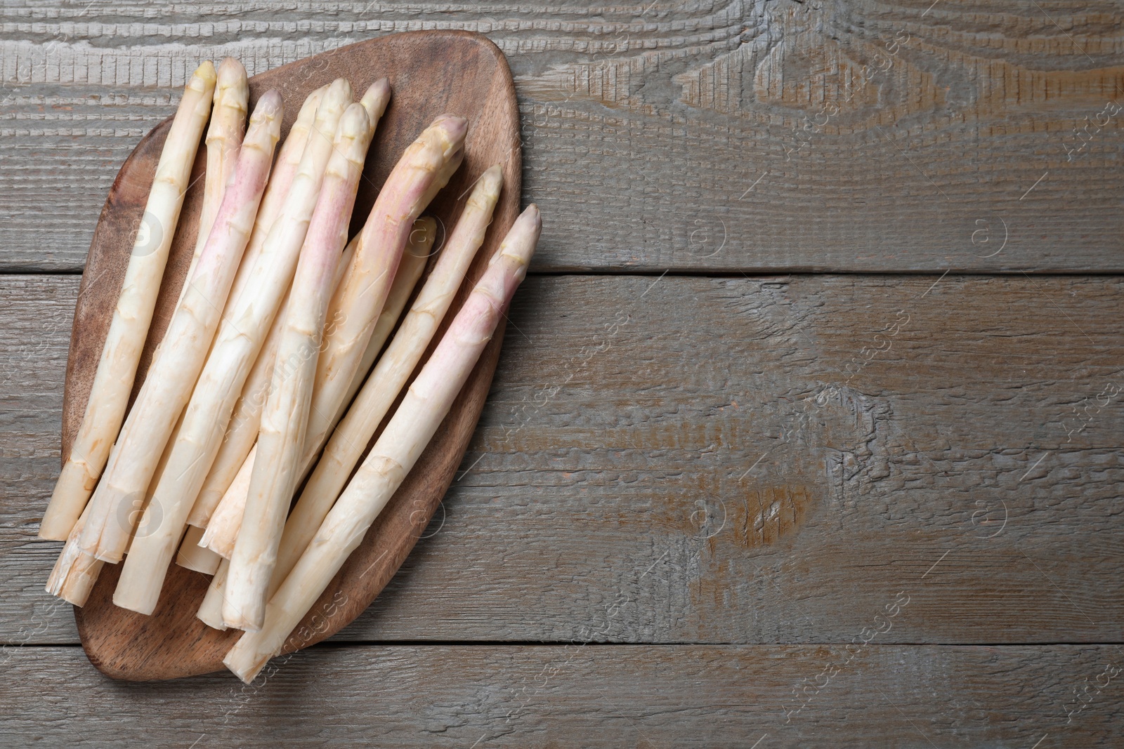 Photo of Fresh white asparagus on wooden table, top view. Space for text