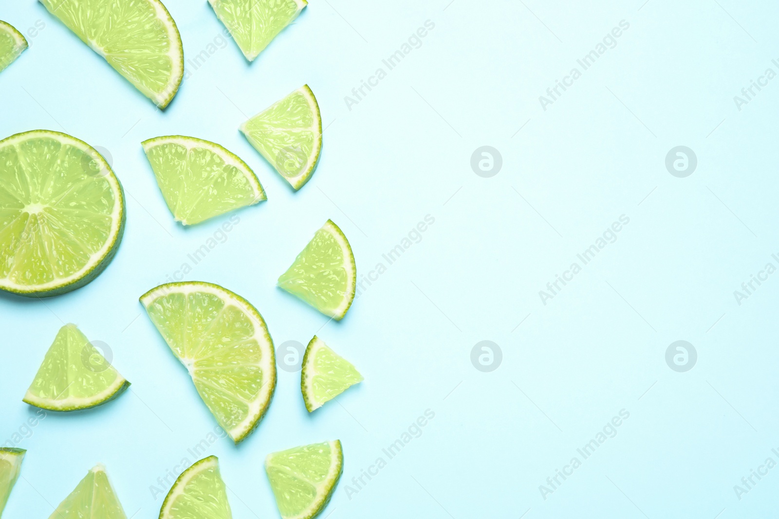 Photo of Juicy fresh lime slices on light blue background, flat lay. Space for text