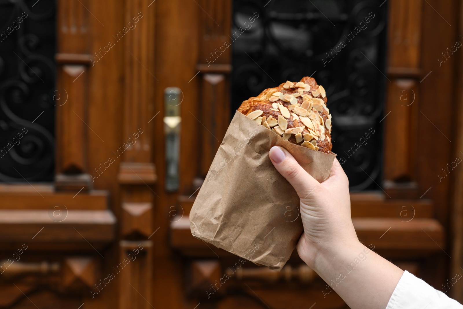 Photo of Woman with delicious croissant outdoors, closeup. Space for text