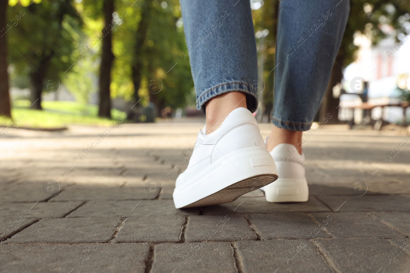 Photo of Woman in stylish sneakers walking on city street, closeup. Space for text