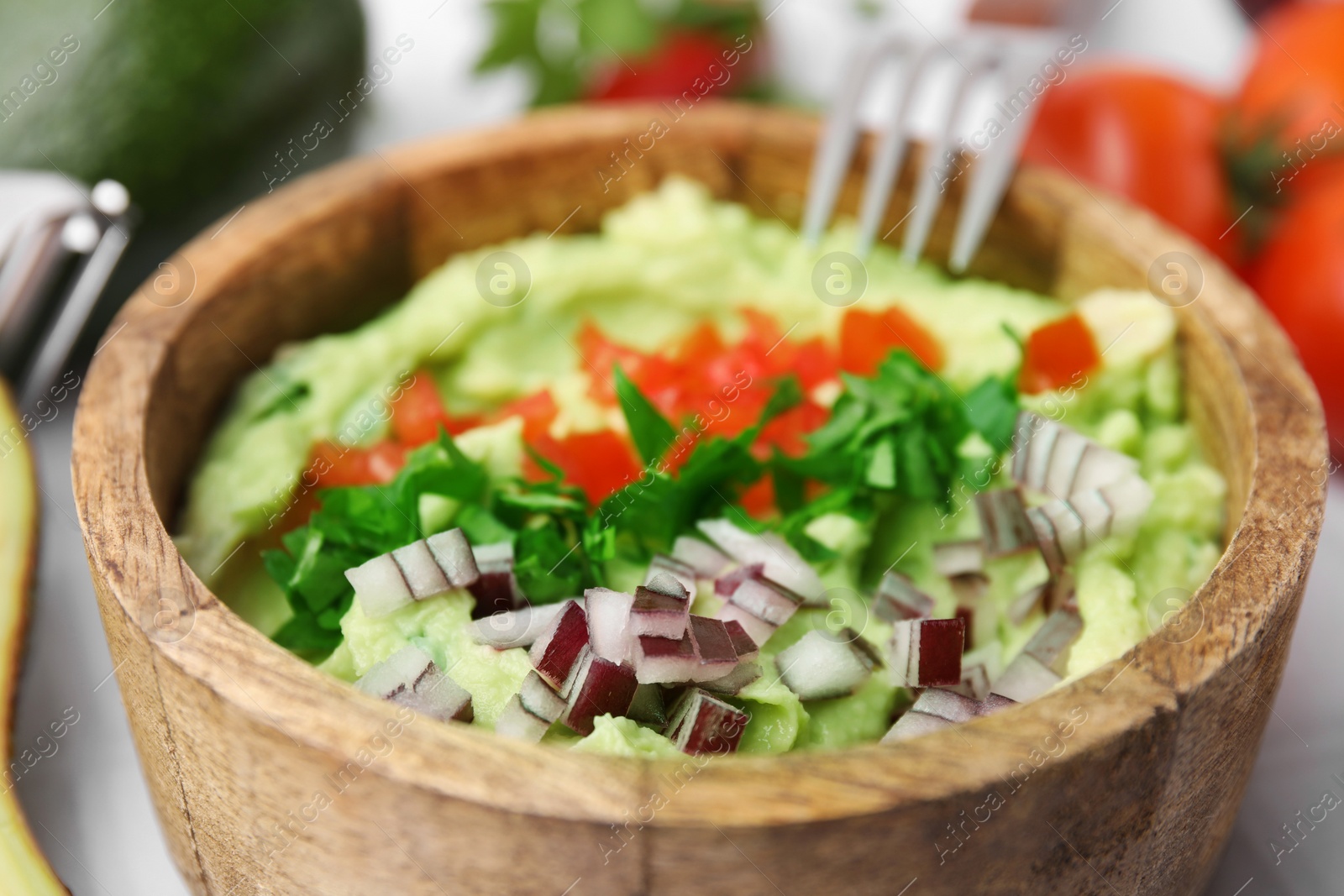 Photo of Bowl of delicious guacamole with onion, tomatoes and ingredients, closeup